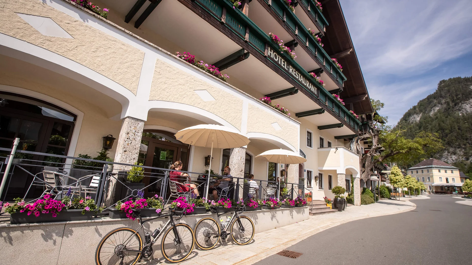 Roadbike-Bucketlist im Salzburger Land – Salzkammergut © Erwin Haiden Außenbereich eines Hotels mit Terrasse, Fahrrad und Bergen im Hintergrund