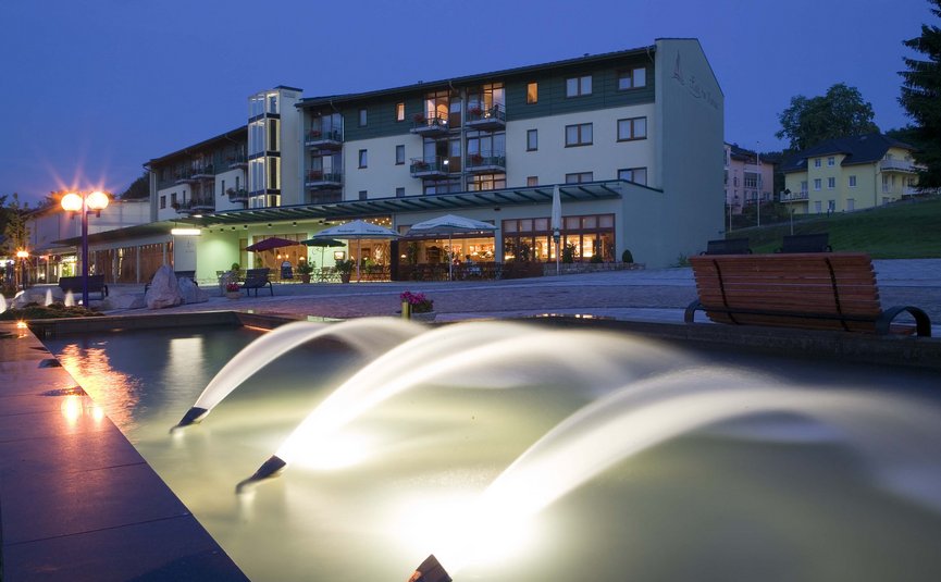 Fontane d'acqua illuminate davanti a un hotel al crepuscolo