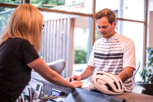 Fietsvakanties © Fabian Schaiter Man in sportkleding die incheckt bij de receptie met een fietshelm op de balie