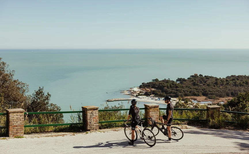 Zwei Radfahrer auf Bergstraße mit Meerblick bei sonnigem Wetter