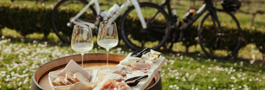 Degustazione di vino con pane, salumi e due biciclette sullo sfondo