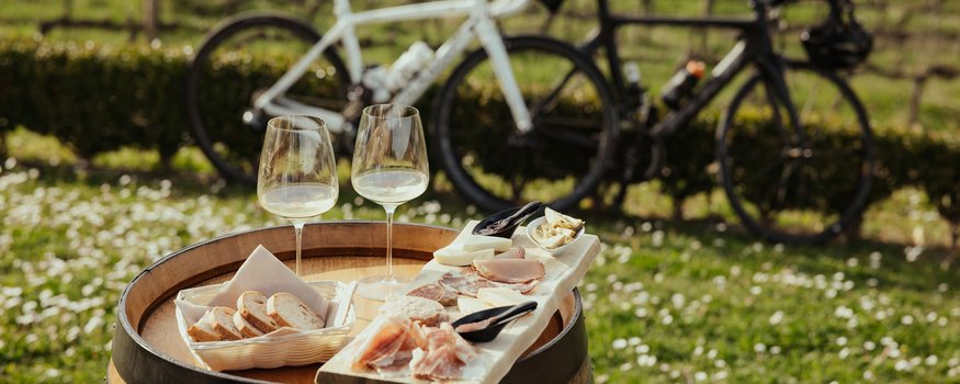 Weinprobe mit Brot, Aufschnitt und zwei Fahrrädern im Hintergrund
