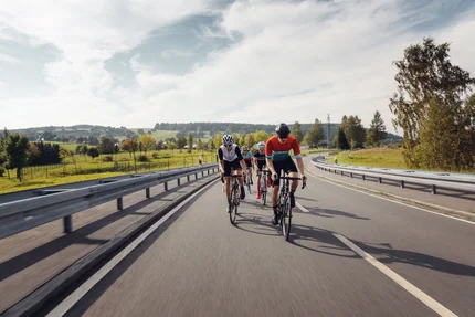 Vier fietsers rijden op een landweg door een groen landschap.