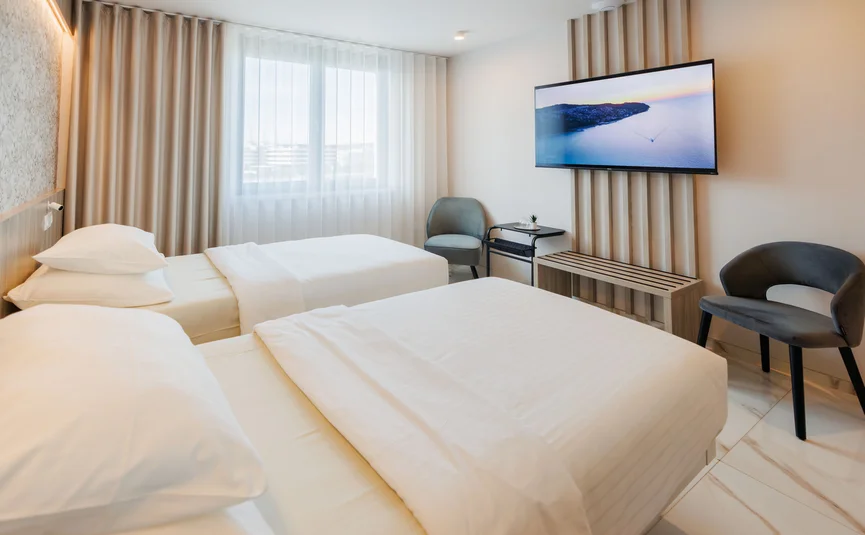 Hotel Capris **** © Foto Jaka Ivančič Enhanced NR Moderne hotelkamer met twee bedden, stoelen en aan de wand gemonteerde tv