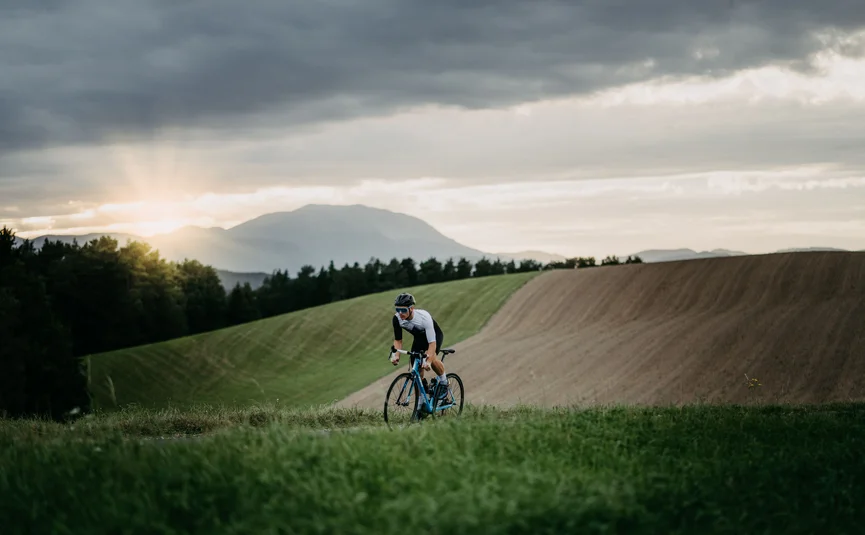 Ciclista che pedala in un paesaggio collinare al tramonto