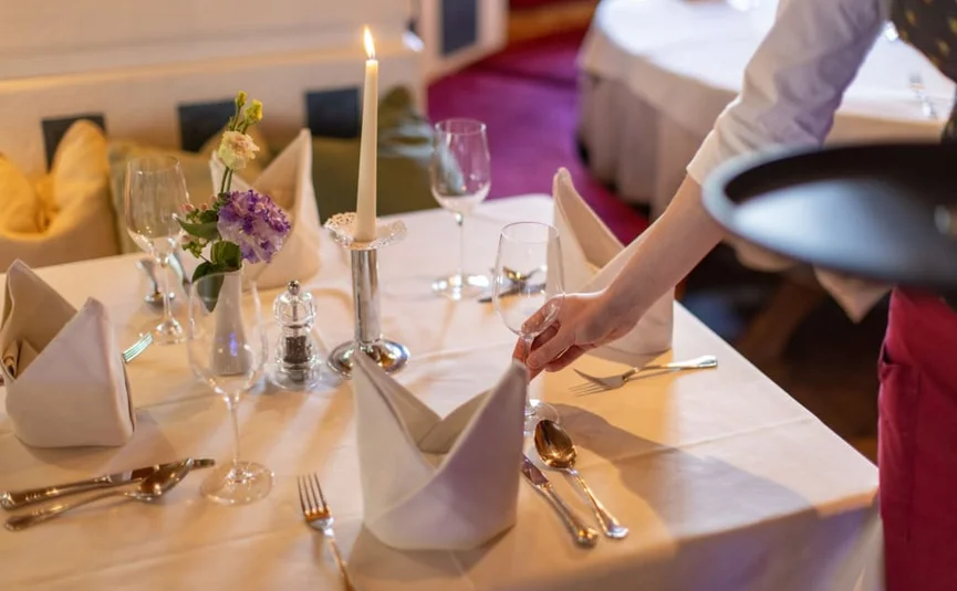 Tavolo elegante apparecchiato in ristorante con cameriere.