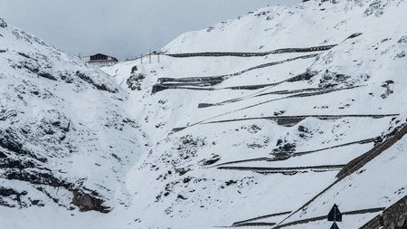 Serpentinenstraße im verschneiten Berggebiet mit Geschwindigkeitsanzeige 130