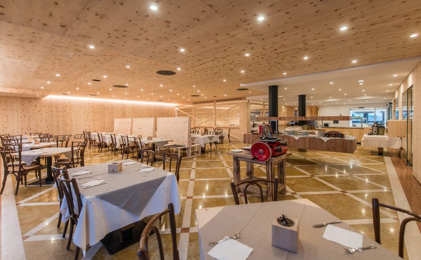 Sala da pranzo ampia e luminosa con sedie in legno e tavoli apparecchiati