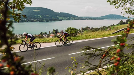 Ein Rennrad-Wochenende im SalzburgerLand – Salzkammergut © SalzburgerLand - Stefan Schopf for WOM Medien Zwei Radfahrer auf Landstraße mit Berg- und Seeblick