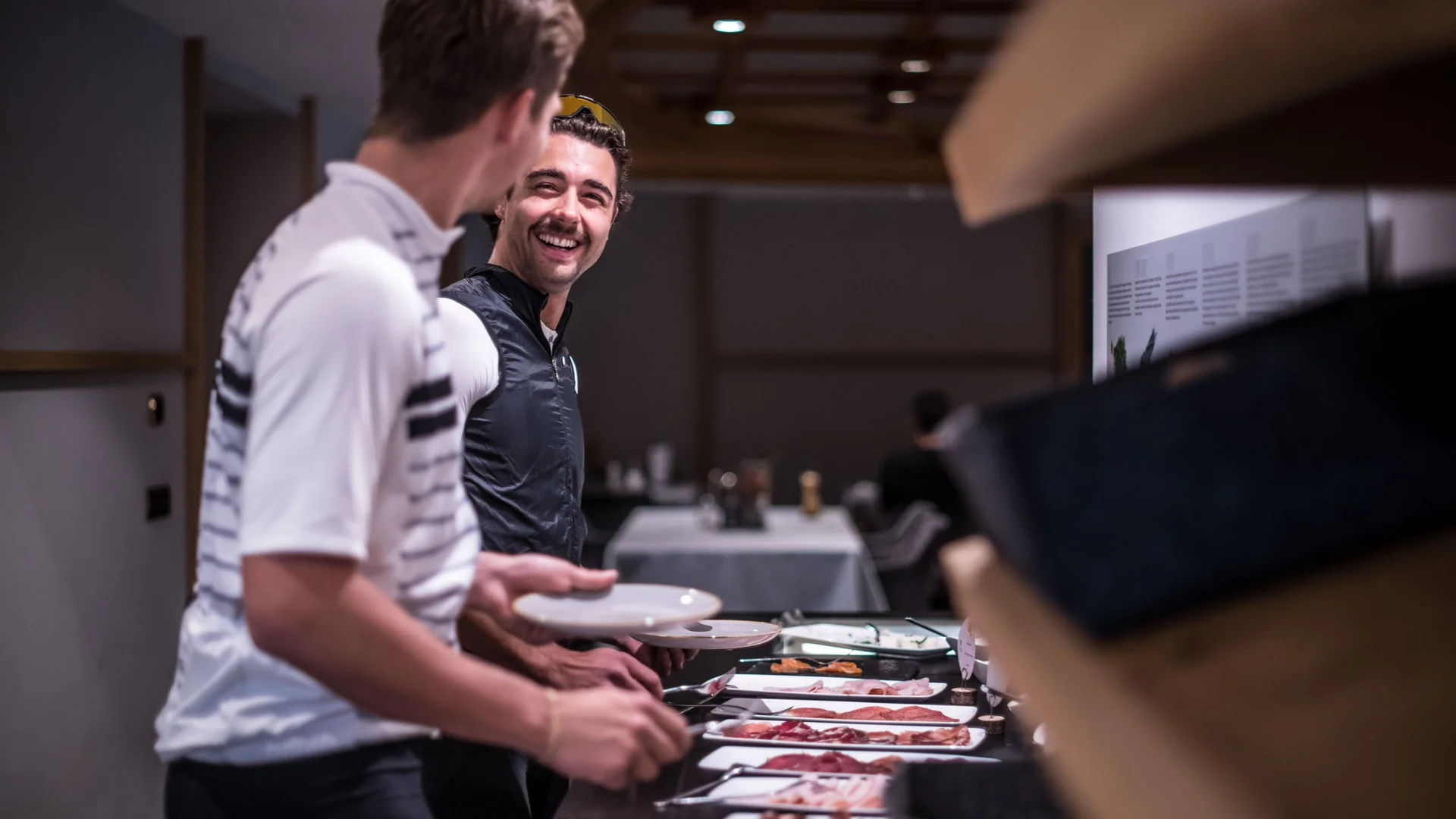 Zwei Männer am Buffet mit Tellern und verschiedenen Fleischplatten
