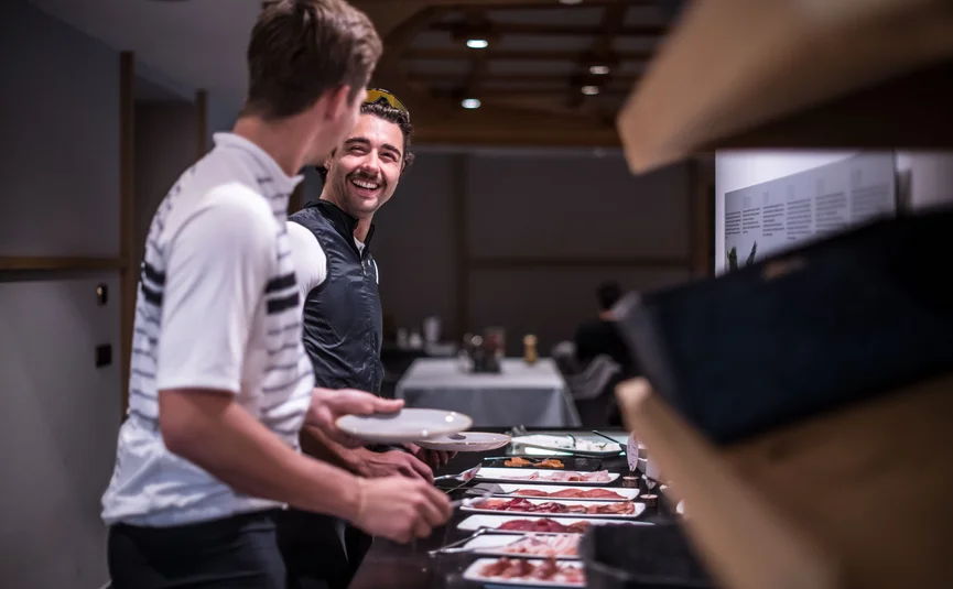 Zwei Männer am Buffet mit Tellern und verschiedenen Fleischplatten