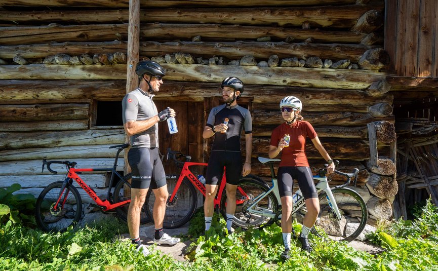 Three cyclists resting with bikes in front of a wooden cabin