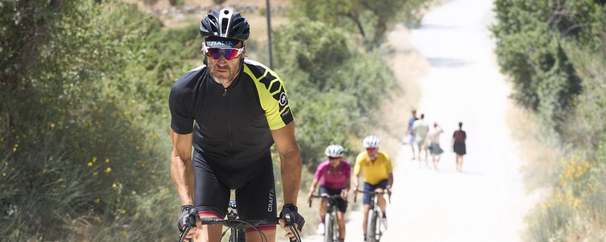 Toskana © Asha Balogh Mann in Radkleidung fährt Fahrrad bergauf auf Schotterweg
