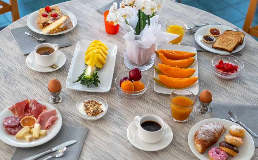 Breakfast table with fruit, pastries, eggs, coffee, and juice