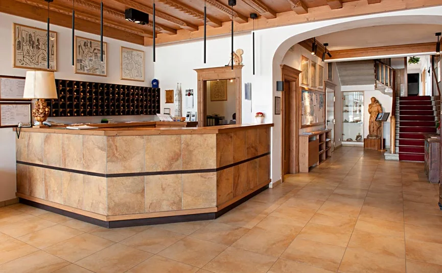 Hotel reception area with wooden counter and staircase with red carpet