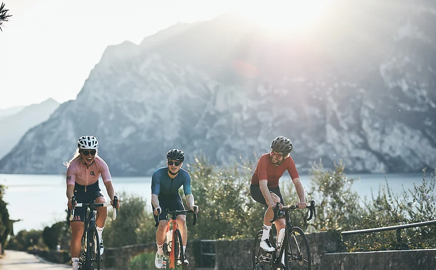 Tre ciclisti che pedalan su una strada di montagna al sole