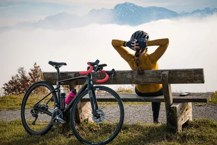 Ein Rennrad-Wochenende im SalzburgerLand – Salzkammergut © A Swiss with a pluse Radfahrerin sitzt auf Bank mit Blick auf Berge und Nebel