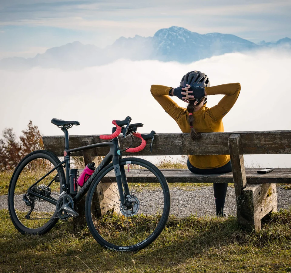 Ein Rennrad-Wochenende im SalzburgerLand – Salzkammergut © A Swiss with a pluse Radfahrerin sitzt auf Bank mit Blick auf Berge und Nebel