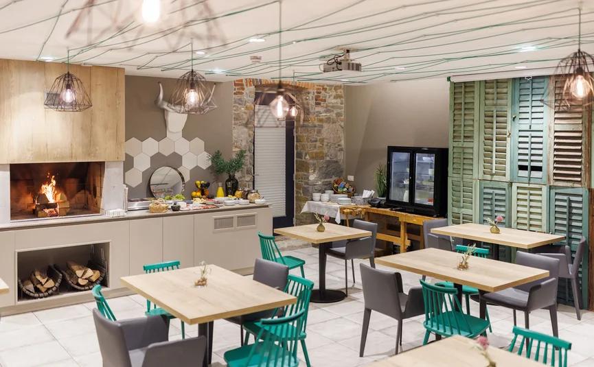 Hotel Vila Robida *** © Jaka Ivancic Cozy dining room with fireplace, tables, chairs, and buffet