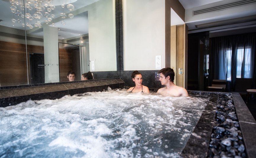 A couple relaxes in a bubbling indoor hot tub