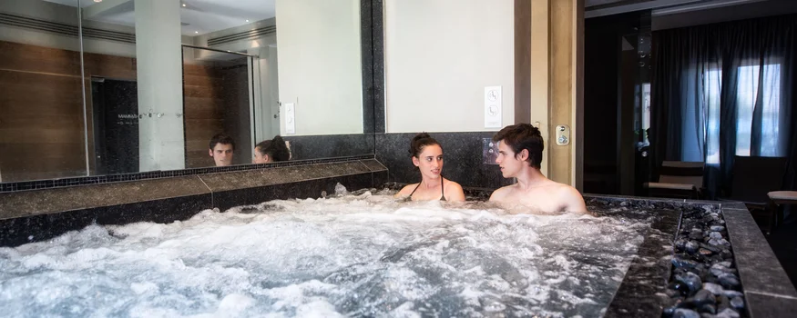 A couple relaxes in a bubbling indoor hot tub