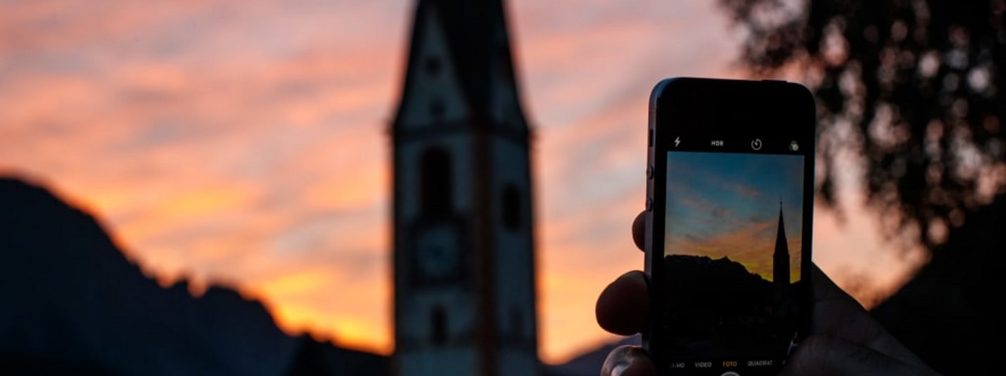 Smartphone capturing church and mountains at sunset