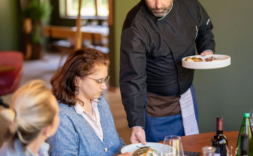 Cuoco serve un piatto agli ospiti in un ristorante con arredi moderni