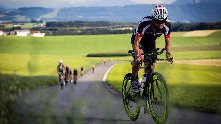 Ein Rennrad-Wochenende im SalzburgerLand – Salzkammergut © Trumer Triathlon Radfahrer in Radrennbekleidung auf Landstraße mit grüner Landschaft im Hintergrund