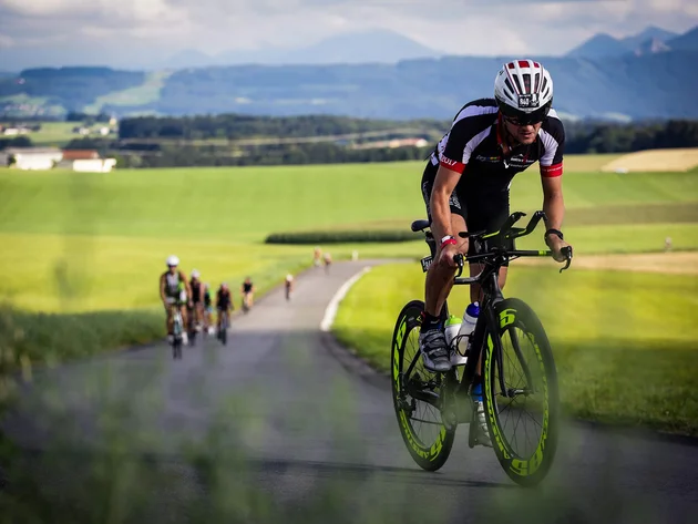 Ein Rennrad-Wochenende im SalzburgerLand – Salzkammergut © Trumer Triathlon Radfahrer in Radrennbekleidung auf Landstraße mit grüner Landschaft im Hintergrund