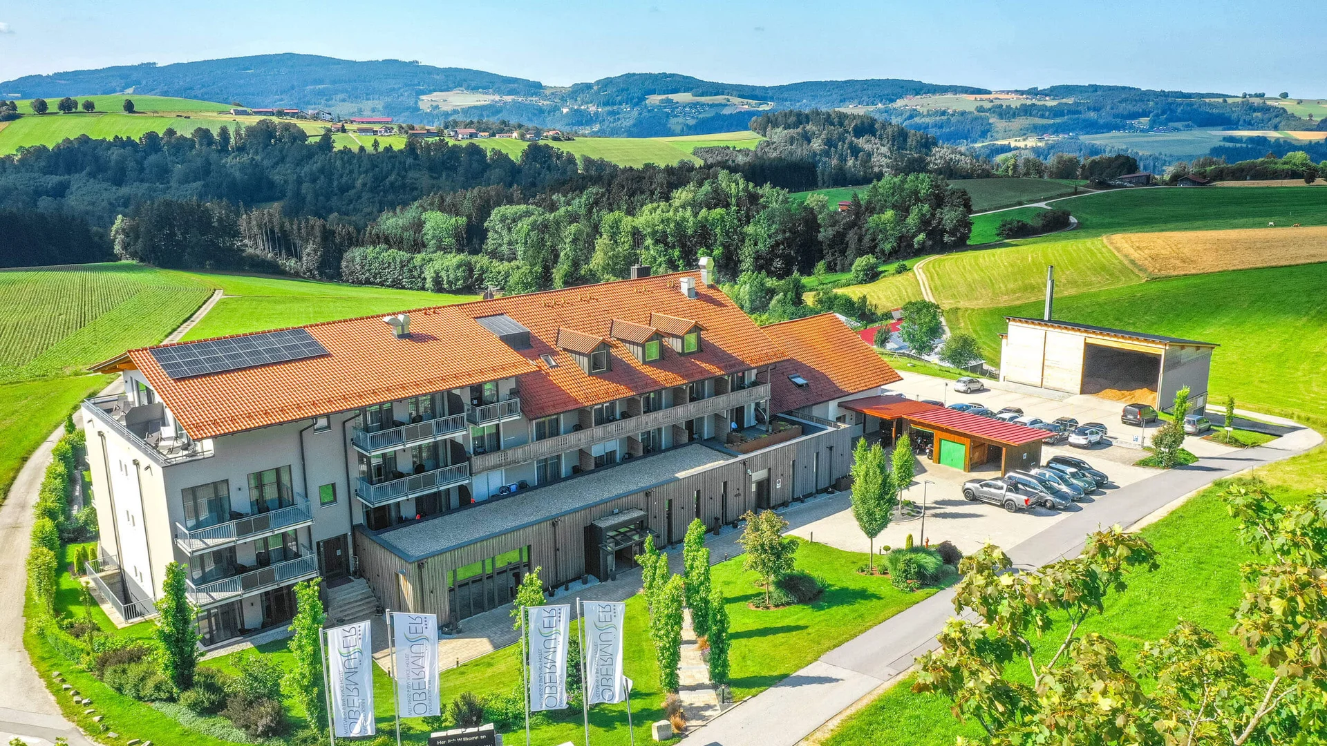 Modern building with red roof and cars in green hilly landscape