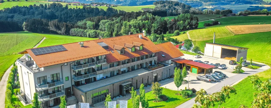 Modern building with red roof and cars in green hilly landscape