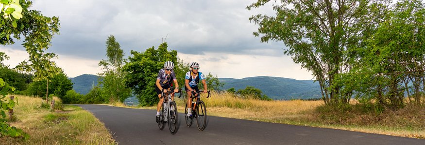 Due ciclisti su una strada di campagna tranquilla con colline sullo sfondo