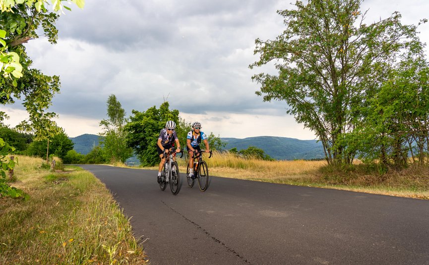 Due ciclisti su una strada di campagna tranquilla con colline sullo sfondo
