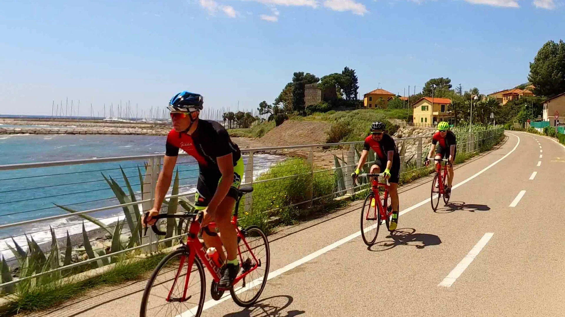 Three cyclists riding on a coastal bike path on a sunny day
