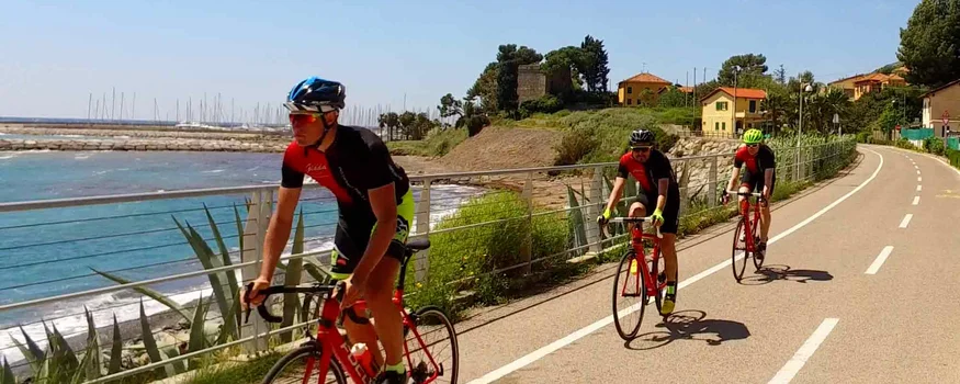 Three cyclists riding on a coastal bike path on a sunny day