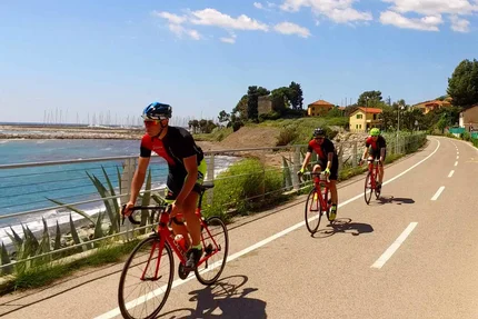 Three cyclists riding on a coastal bike path on a sunny day