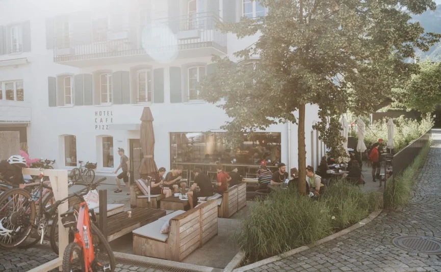 Sonniges Café mit Außensitzplätzen und Fahrrädern vor einem Hotel