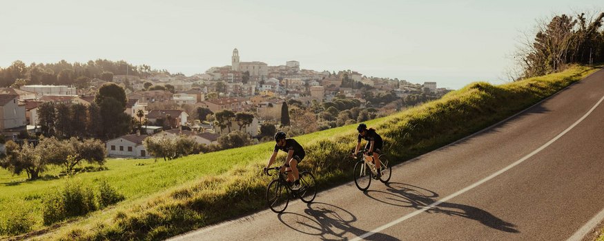 Zwei Radfahrer fahren auf der Straße mit einer Stadt im Hintergrund
