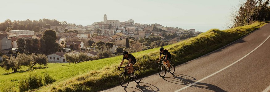 Due ciclisti su una strada con una città sullo sfondo