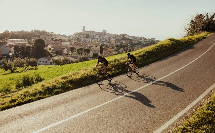 Due ciclisti su una strada con una città sullo sfondo
