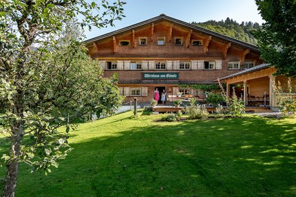 Traditional inn with green lawn and fruit trees in front