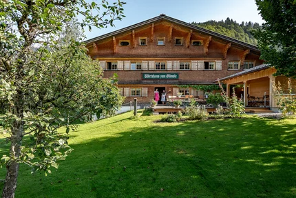 Traditioneel gastenhuis met groen gazon en fruitbomen vooraan