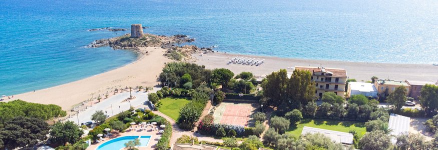 Aerial view of a coastal resort with pool, beach, and historic tower