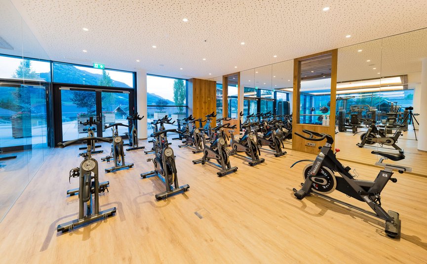 Gym with multiple stationary bikes in front of large windows and mirrored wall