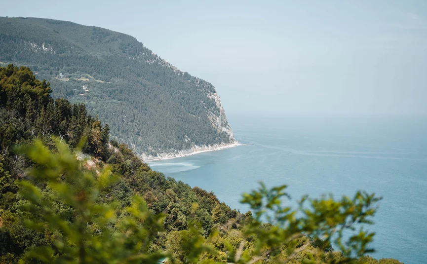 Berglandschaft mit grünem Wald und Meer im Hintergrund unter blauem Himmel