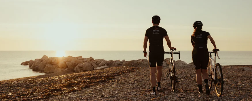 Saisonstart am Meer © Alex Moling Zwei Radfahrer bei Sonnenuntergang am Strand mit Blick aufs Meer