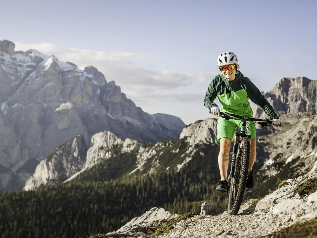 Donna con casco in mountain bike su percorso di montagna con montagne sullo sfondo
