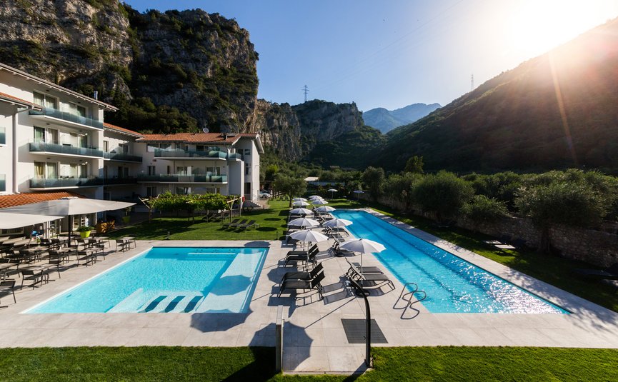 Hotel mit zwei Pools und Sonnenliegen vor Berglandschaft bei Sonnenuntergang