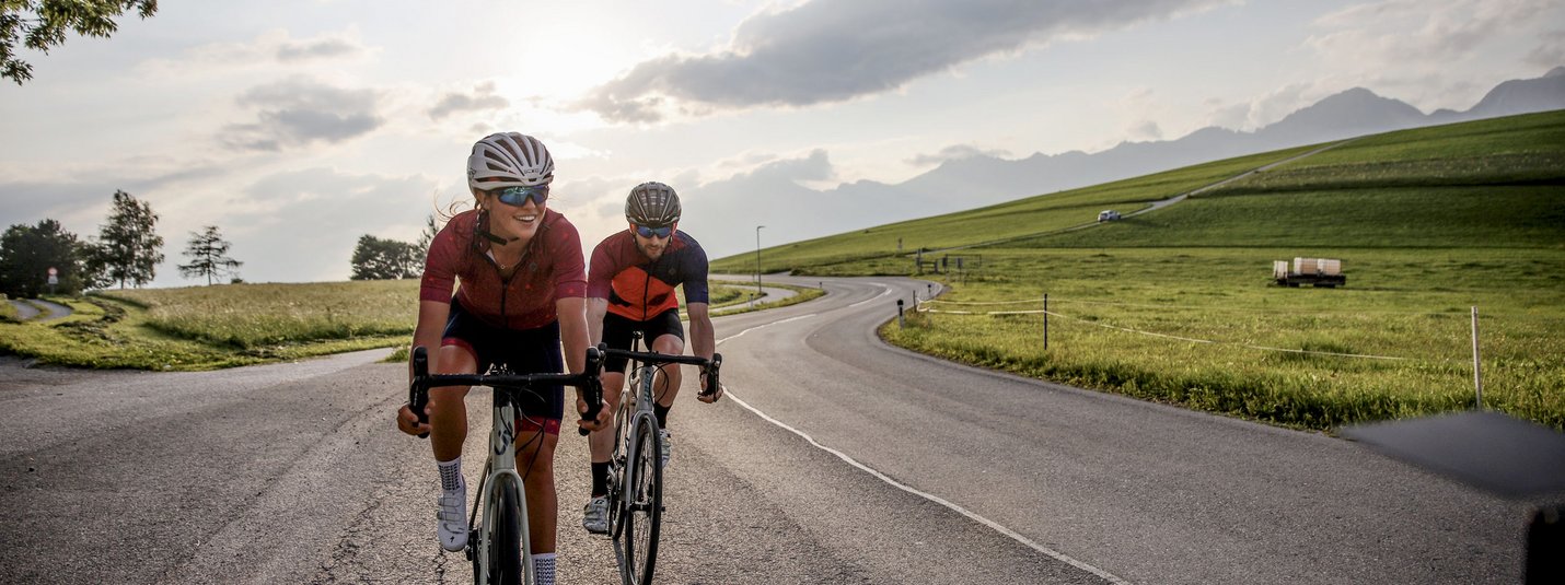 Due ciclisti pedalano su una strada di campagna al tramonto