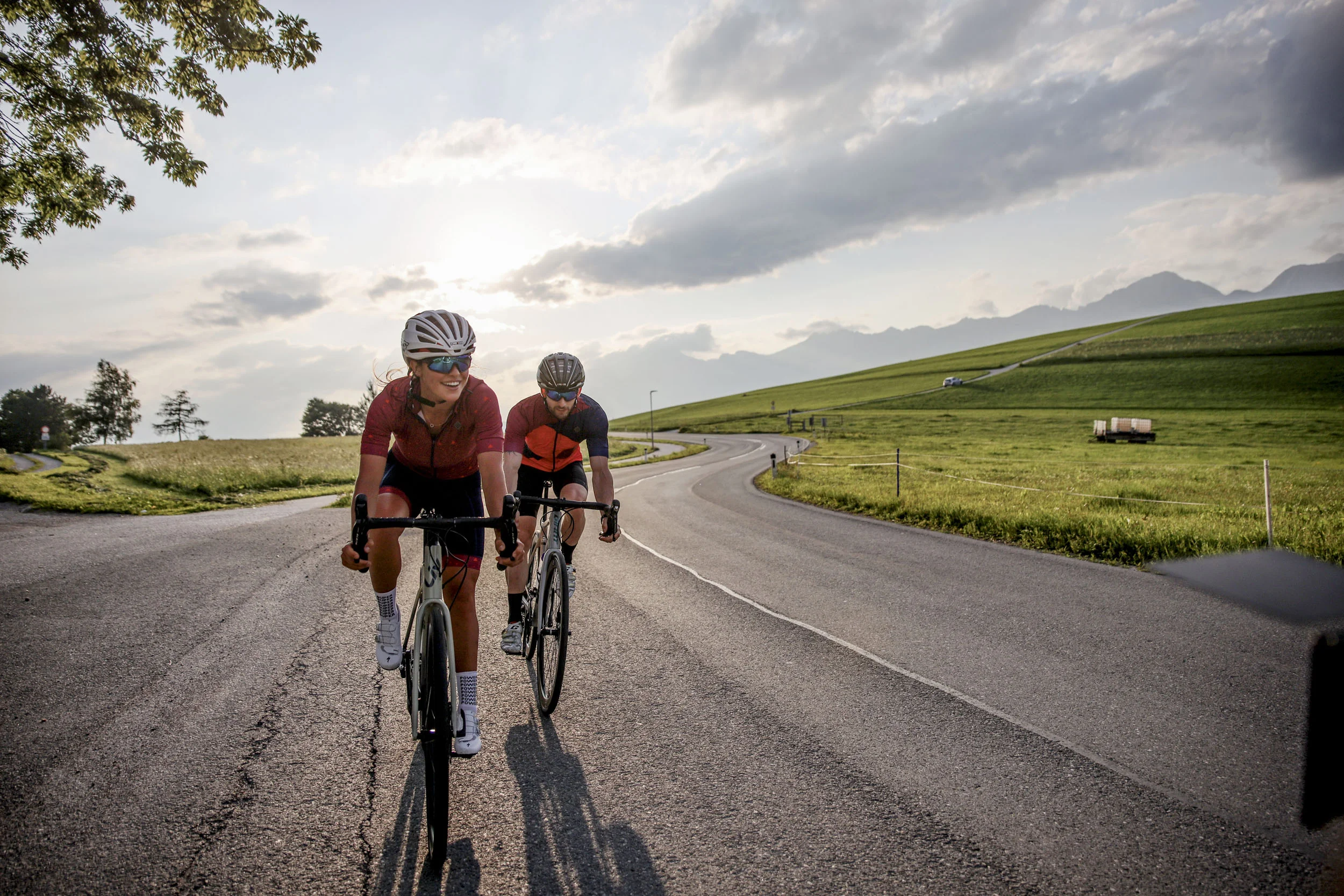 Zwei Radfahrer fahren auf einer Landstraße bei Sonnenuntergang